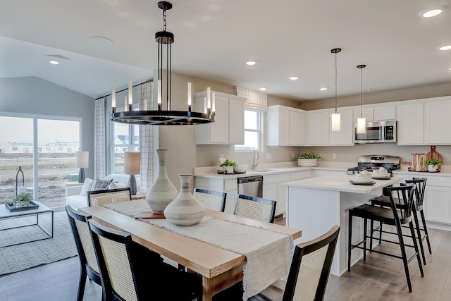 dining area featuring light hardwood / wood-style flooring, vaulted ceiling, and sink