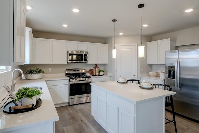 kitchen with appliances with stainless steel finishes, a center island, white cabinetry, and hanging light fixtures