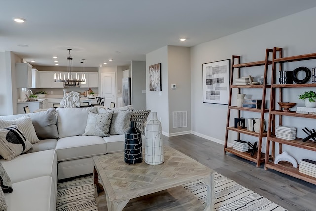 living room with light hardwood / wood-style floors, a notable chandelier, and sink