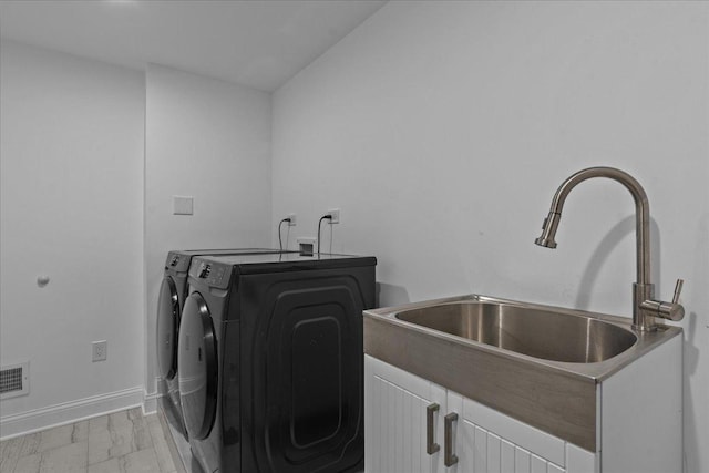 washroom with cabinets, washer and clothes dryer, and sink