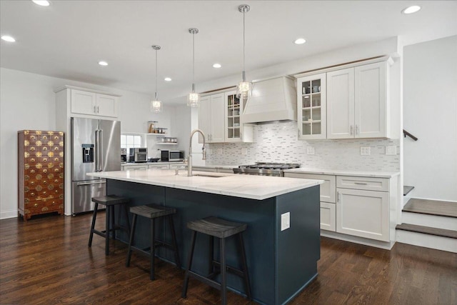 kitchen with stainless steel appliances, custom exhaust hood, white cabinetry, and sink