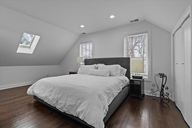 bedroom with a closet, dark hardwood / wood-style flooring, and lofted ceiling with skylight