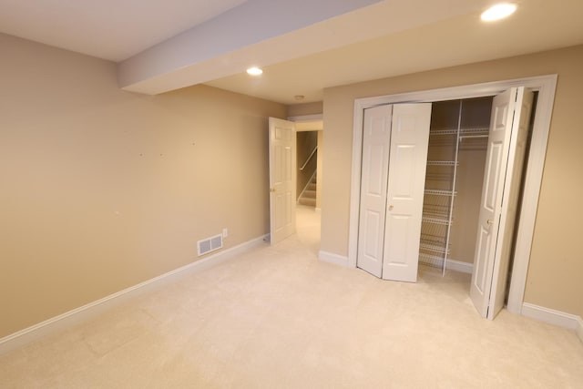 unfurnished bedroom with light colored carpet and a closet