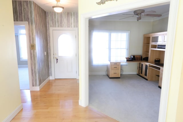 foyer featuring ceiling fan, crown molding, and light colored carpet