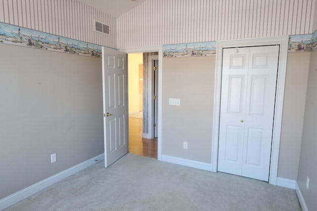 unfurnished bedroom with a closet and light carpet