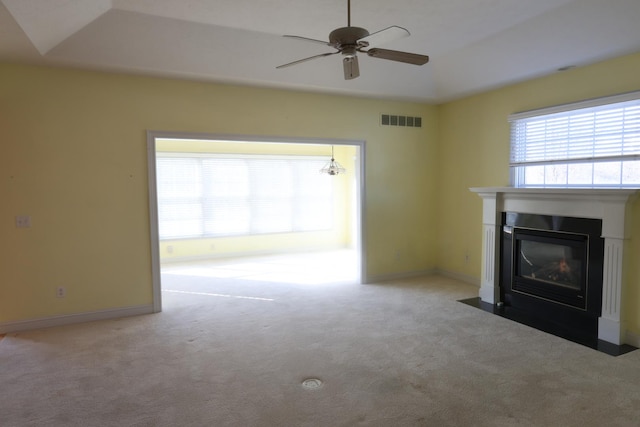 unfurnished living room featuring a raised ceiling, ceiling fan, and light colored carpet