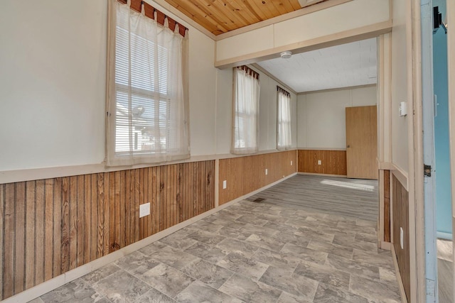 spare room with wood walls, wooden ceiling, and ornamental molding