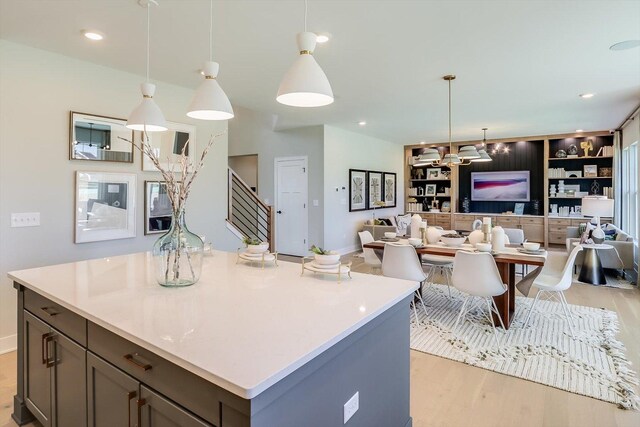 kitchen with built in shelves, light hardwood / wood-style floors, and hanging light fixtures