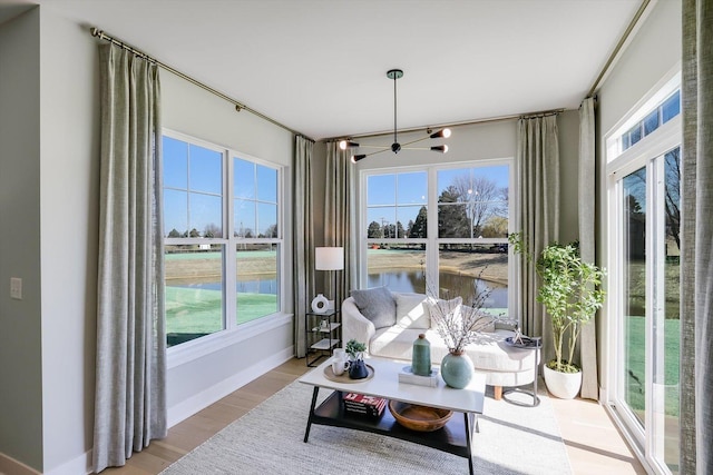 sunroom with ceiling fan, a healthy amount of sunlight, and a water view