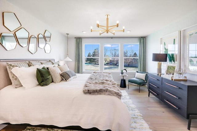 bedroom with light hardwood / wood-style floors and an inviting chandelier