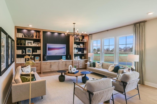 living room featuring built in features, light wood-type flooring, and an inviting chandelier