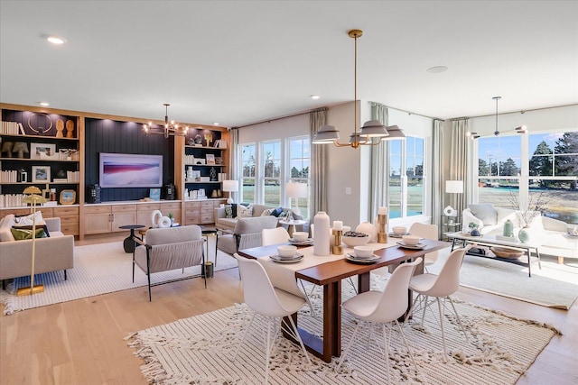 dining room with built in shelves, light hardwood / wood-style flooring, and a notable chandelier