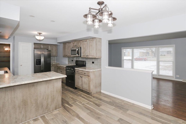 kitchen featuring a chandelier, hanging light fixtures, appliances with stainless steel finishes, hardwood / wood-style flooring, and decorative backsplash