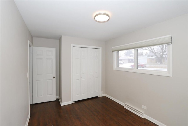 unfurnished bedroom with dark wood-type flooring and a closet