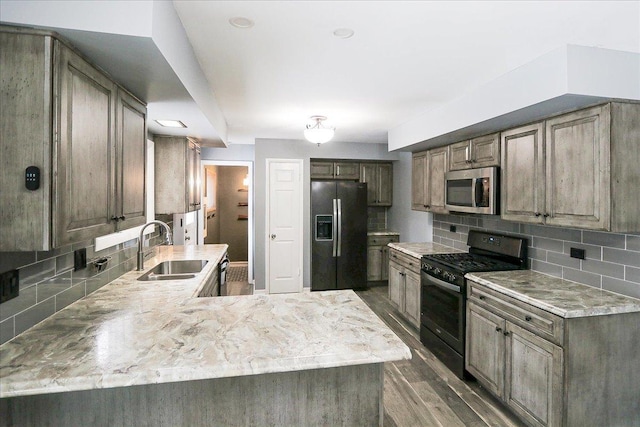 kitchen featuring tasteful backsplash, dark wood-type flooring, sink, and black appliances