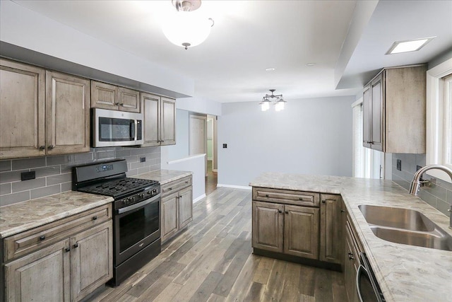 kitchen featuring appliances with stainless steel finishes, sink, dark hardwood / wood-style flooring, decorative backsplash, and kitchen peninsula