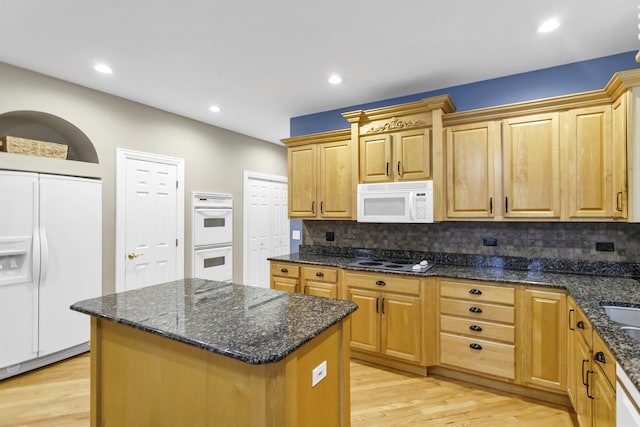 kitchen featuring light hardwood / wood-style floors, decorative backsplash, white appliances, dark stone countertops, and a kitchen island