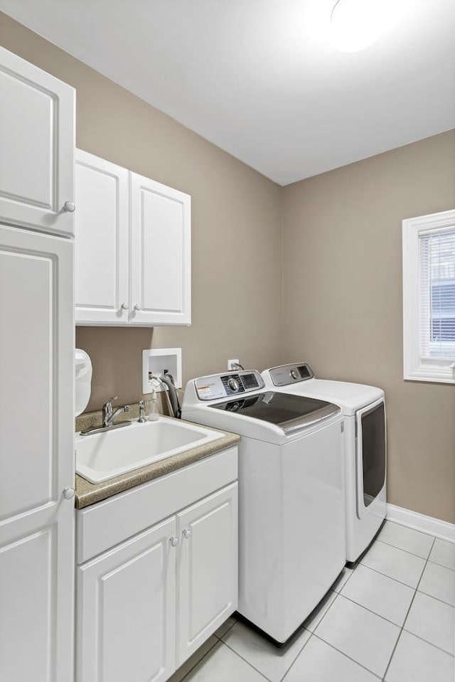 washroom with cabinets, light tile patterned floors, washer and clothes dryer, and sink