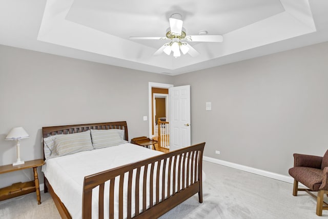 carpeted bedroom with ceiling fan and a tray ceiling