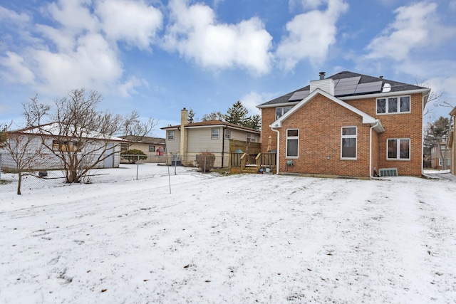 snow covered property with central AC unit and solar panels