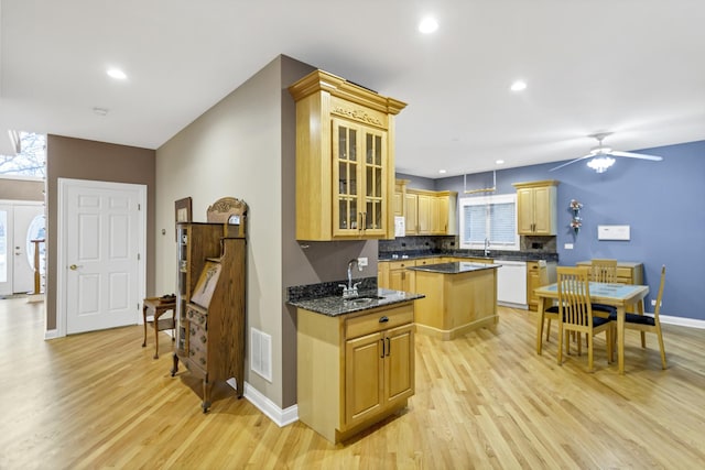 kitchen featuring ceiling fan, dishwasher, a kitchen island, sink, and light hardwood / wood-style flooring