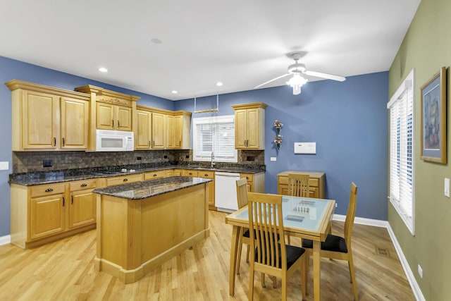 kitchen featuring light hardwood / wood-style flooring, dark stone countertops, white appliances, and a kitchen island