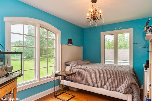 bedroom with wood-type flooring, an inviting chandelier, and multiple windows