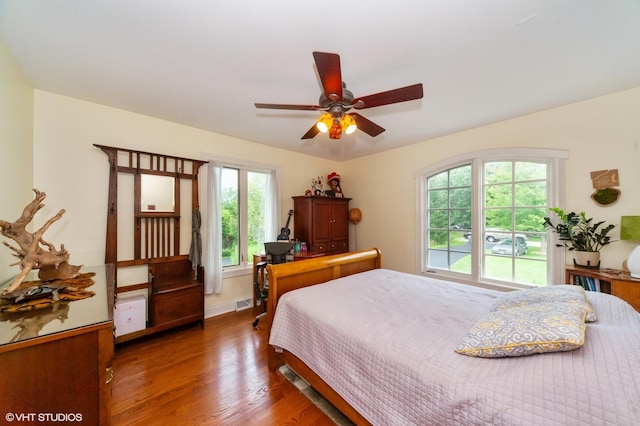 bedroom with multiple windows, dark hardwood / wood-style flooring, and ceiling fan