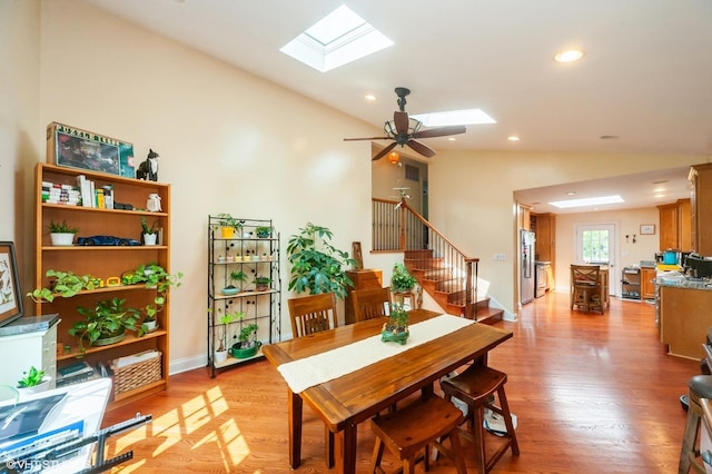 dining room with vaulted ceiling with skylight, ceiling fan, and light hardwood / wood-style flooring