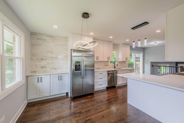 kitchen with pendant lighting, white cabinets, kitchen peninsula, and appliances with stainless steel finishes