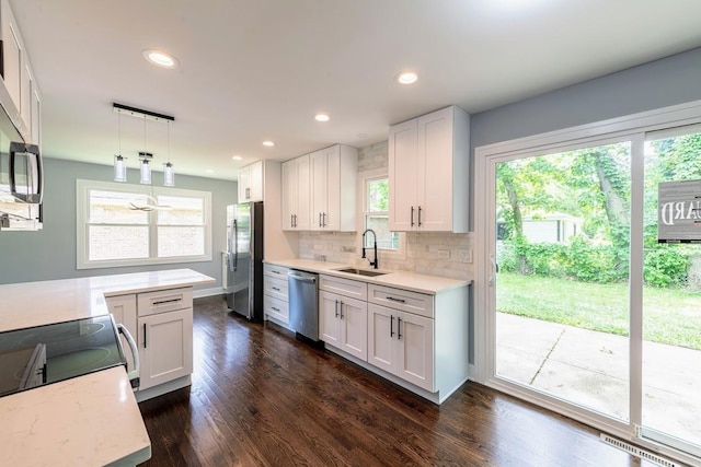 kitchen with white cabinets, appliances with stainless steel finishes, hanging light fixtures, and sink