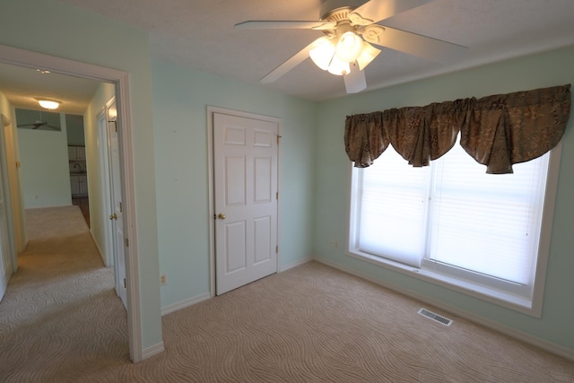 unfurnished bedroom with ceiling fan and light colored carpet