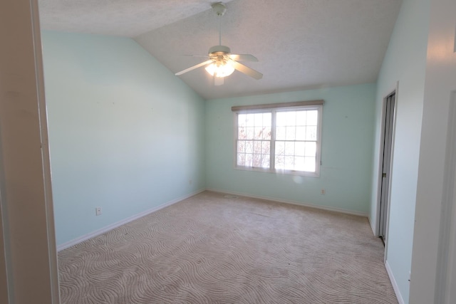 carpeted spare room featuring a textured ceiling, ceiling fan, and vaulted ceiling