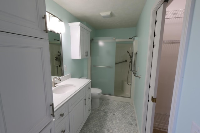 bathroom featuring toilet, a shower with shower door, and vanity