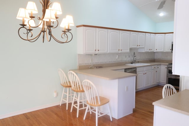 kitchen featuring kitchen peninsula, decorative backsplash, ceiling fan with notable chandelier, white cabinets, and sink