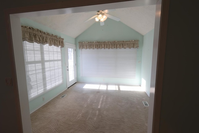 empty room with lofted ceiling, light colored carpet, and ceiling fan