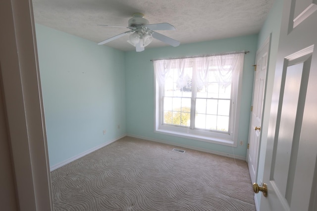 carpeted spare room featuring a textured ceiling and ceiling fan