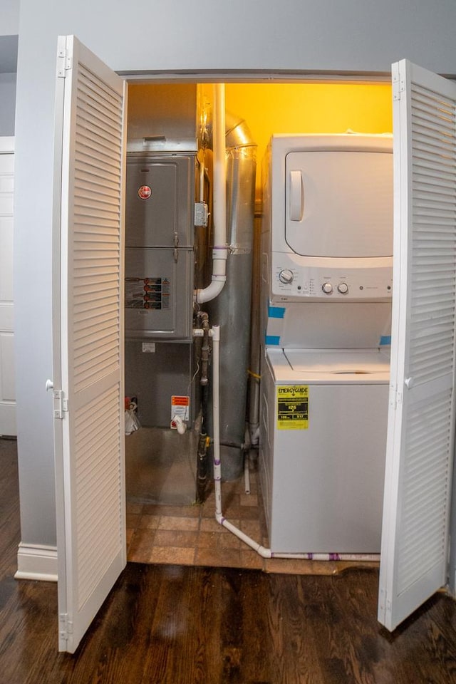 clothes washing area with stacked washer / drying machine and dark hardwood / wood-style flooring