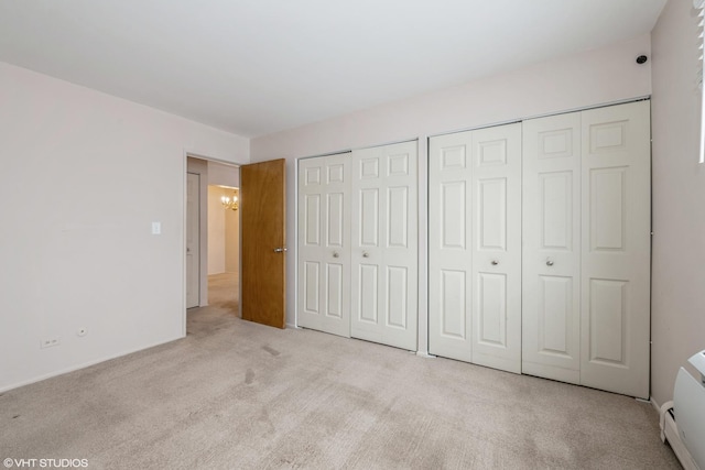 unfurnished bedroom with a chandelier, light carpet, and two closets