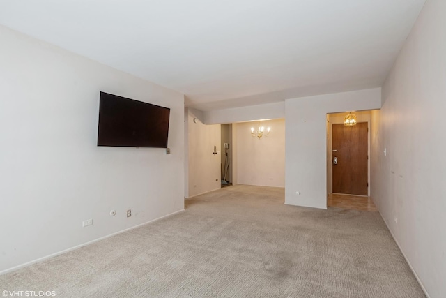 empty room featuring light carpet and a notable chandelier