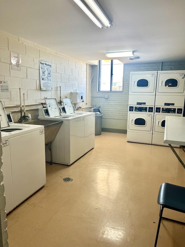 clothes washing area featuring washing machine and dryer, sink, and stacked washer and clothes dryer