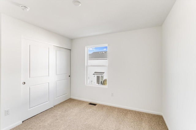 unfurnished bedroom featuring light colored carpet and a closet