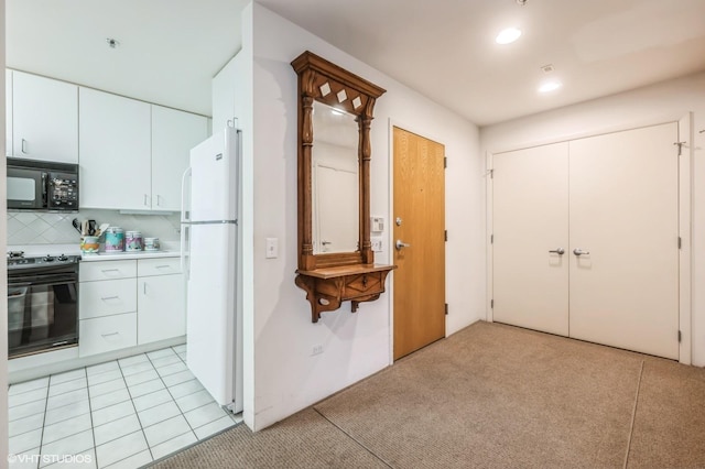 kitchen with stove, backsplash, white cabinets, light tile patterned floors, and white fridge