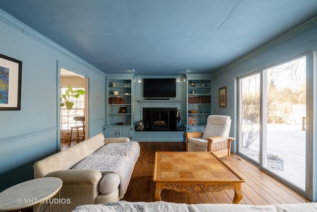 living room with crown molding, hardwood / wood-style floors, and built in shelves