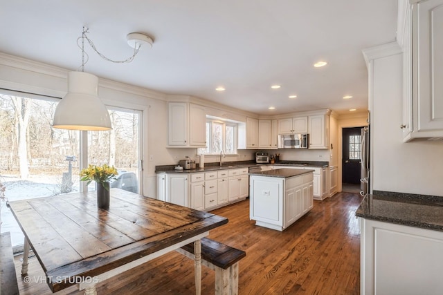 kitchen with sink, a center island, hanging light fixtures, dark hardwood / wood-style flooring, and white cabinets