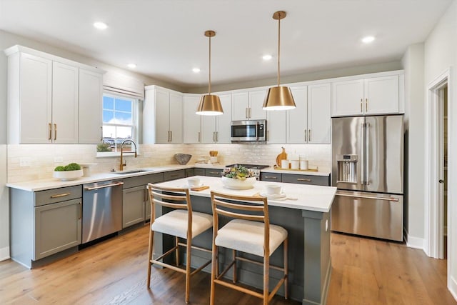 kitchen featuring appliances with stainless steel finishes, sink, pendant lighting, a center island, and gray cabinets