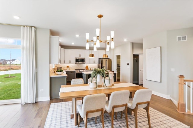 dining space with light wood-type flooring and an inviting chandelier