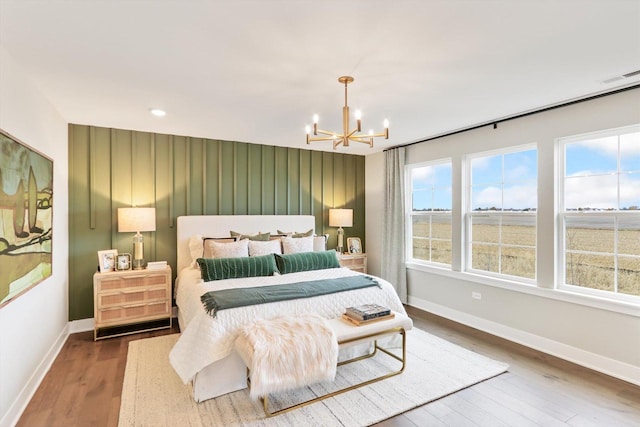 bedroom featuring multiple windows, wood-type flooring, and an inviting chandelier