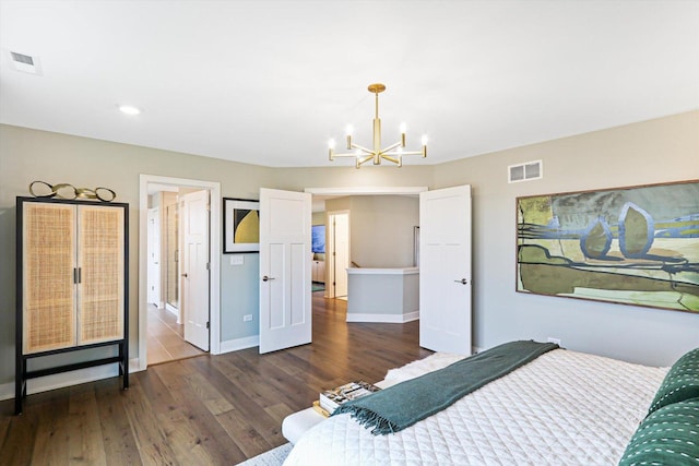 bedroom featuring ensuite bathroom, an inviting chandelier, and dark wood-type flooring