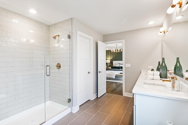 bathroom with a shower with door, vanity, and an inviting chandelier